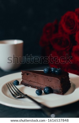 
white cup of tea with cheesecake and a bouquet of red roses