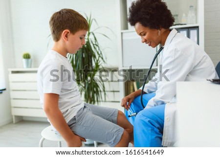 Woman African American doctor general practitioner examining child's patellar knee-jerk reflex