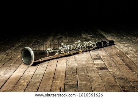 black woodwind clarinet lies on a brown wooden stage