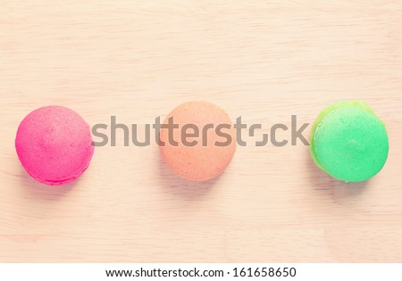 Sweet colorful macaroons on wood with retro filter effect