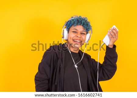 young girl dancing with mobile phone and headphones isolated on color background