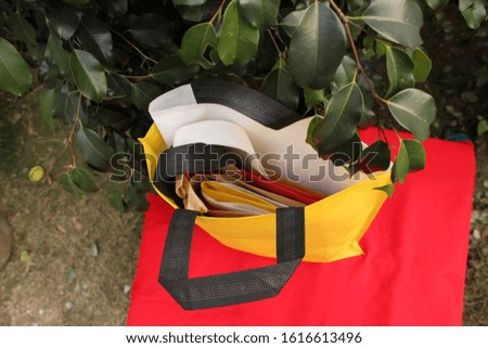 above view Yellow Bag Isolate on Lush Lava 2020 Trends Color Table against green plant leaves. Non Woven Shopping Bag. Recyclable ECO Bag. Environmentally Concept. Reusable Bag for Grocery Shopping. 