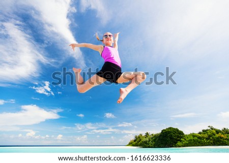 Happy girl jumping at tropical beach having a lot of fun on summer vacation