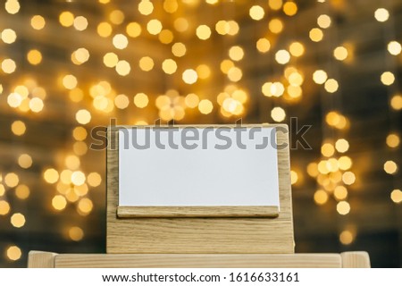 Mock Up calendar - diary on an oak stand white card, . Against the backdrop of a bokeh of stars garland