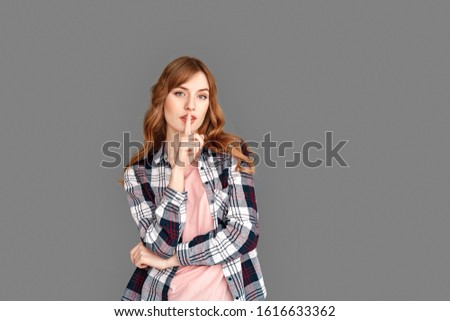 Young stylish woman studio standing isolated on grey background showing quiet gesture to camera serious