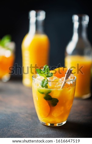 Alcoholic cocktail with vodka, ornage, mint and ice on the black background, selective focus