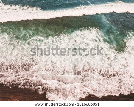 Aerial view of surfers in the waves of the Atlantic ocean. Sandy beach. Panorama background shot on a drone. Selectivity focus