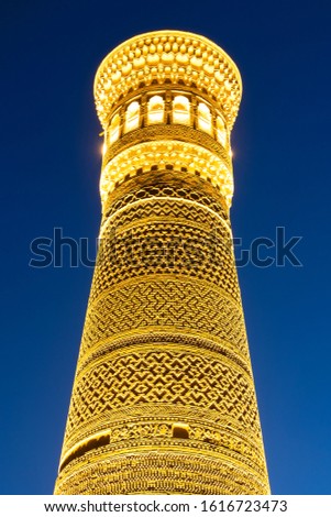 Vertical photo of Great Minaret of the Kalon illuminated during the blue hour. This 48m high minaret is located in Poi Kalan Complex in Bukhara, Uzbekistan. High tower with yellow illumination.