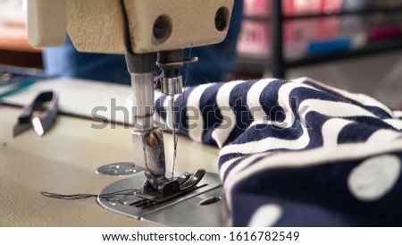 Sewing machine with a needle that has already inserted a thread,  There are cloths near each other.