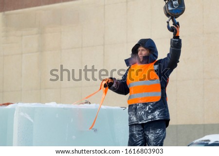 Portrait of a working installer in a reflective vest while unloading ice plates