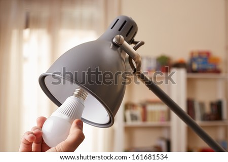 Hand changing a regular light bulb for LED at home Royalty-Free Stock Photo #161681534