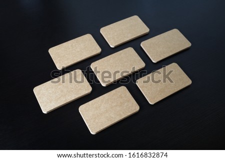 Photo of blank kraft business cards on black wooden background. Template for ID.