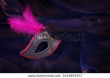 Photo of elegant and delicate pink Venetian mask over purple silk background
