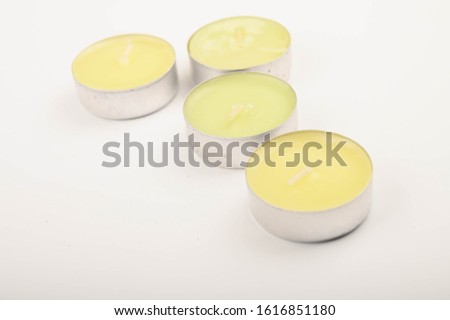 Several small colored candles in aluminum casings on a white background. Close up.
