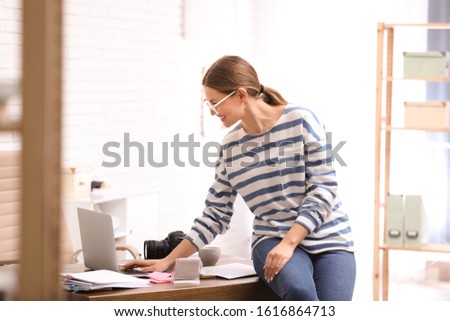 Young journalist working with laptop in light office