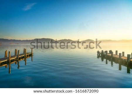 Two wooden piers or jetties and lake at sunrise. Torre del Lago Puccini, Versilia, Massaciuccoli lake, Tuscany, Italy, Europe Royalty-Free Stock Photo #1616872090