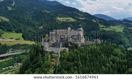Aerial panoramic view of Hohenwerfen Castle, Austria. Medieval rock fortress in Alpine mountains with spruces. Overlooking the Werfen town in Salzach valley. Summer. Royalty-Free Stock Photo #1616874961