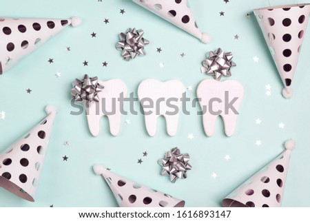 Happy Dentist's Day concept with teeth and holiday caps on a blue background.