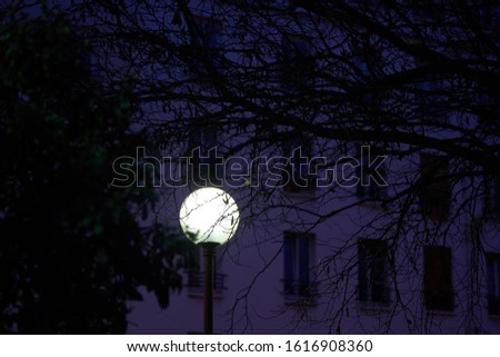 lamppost lit at night in paris in the street blue red white orange background  building
