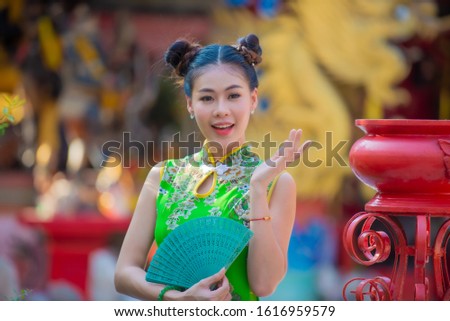Action portrait an Asian woman wearing Cheongsam dress. the celebration of something or chinese new year in a joyful and exuberant way. Festivities and Celebration concept, 