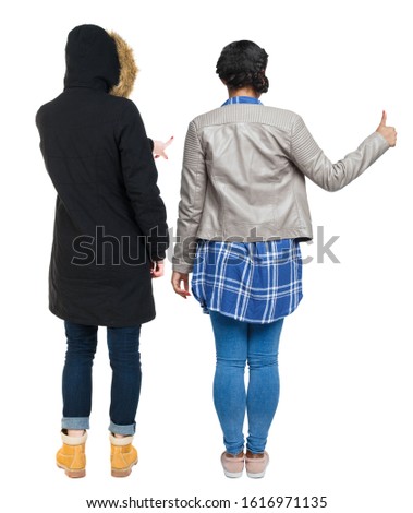 Back view of two young girl in winter jacket showing thumb up. Rear view people collection. backside view of person. beautiful woman friends showing gesture. Rear view. Isolated over white background.