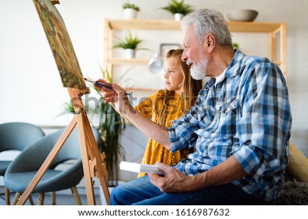 Senior man, grandfather and his grandchild drawing, painting together. Happy family time