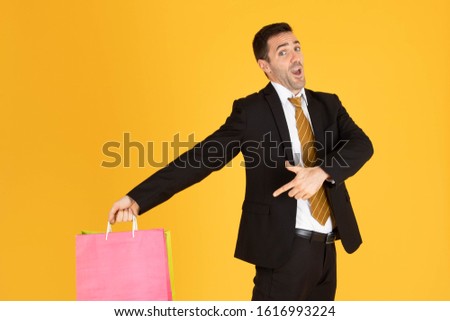 Portrait of businessman with shopping bags on yellow  background.