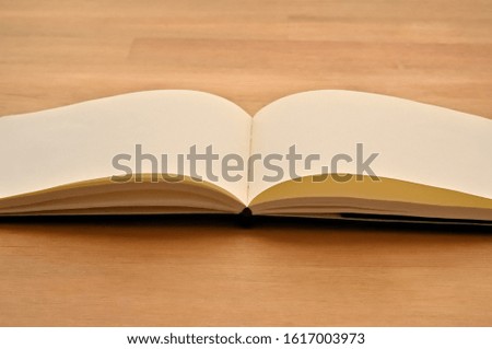 A horizontal notebook is open on wooden board.