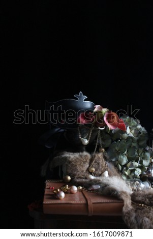 A picture inspired  Netherlands still-life painting, shows jewelry, fur scarf, flowers and a old-styled glass lamp on a wooden table.