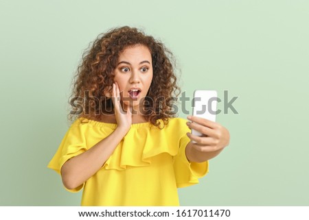 Beautiful young woman taking selfie on color background