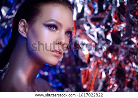 Art fashion glowing make-up. Portrait of a woman posing in studio. Metallic colorful squares on woman face. close-up