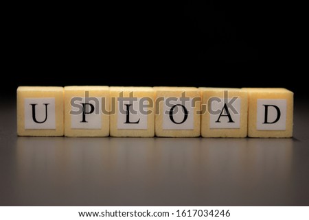 The word UPLOAD written on wooden cubes isolated on a black background...