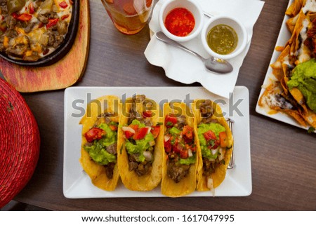 Traditional Mexican tacos with juicy roasted beef, guacamole, fresh vegetables and sauces

