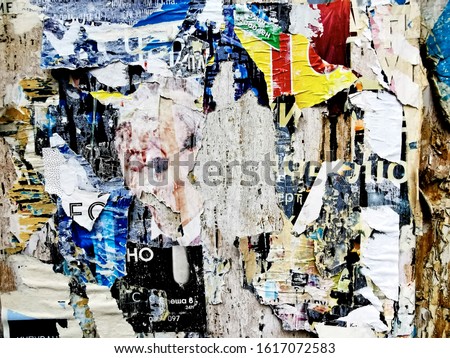 Old torn posters on street wall, grunge background.
