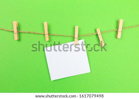 a piece of white paper attached to a rope clothespin on green background 
