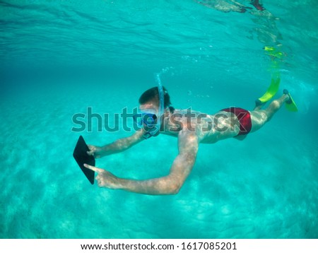Young man swimming underwater touching the blank screen of a digital tablet