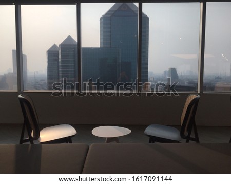 Two chairs are placed by the window at the tall building