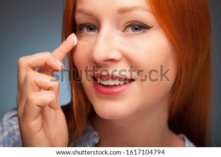 close up photo of young beautyful woman applying cream on her face