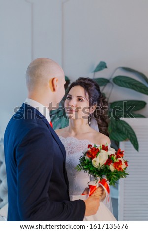 Happy bride and groom in a room hug each other.