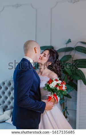 Happy bride and groom in a room hug each other.