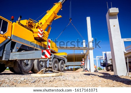 Low angle view on extended side hydraulic outrigger to increase crane stability until is under heavy duty.  Royalty-Free Stock Photo #1617161071