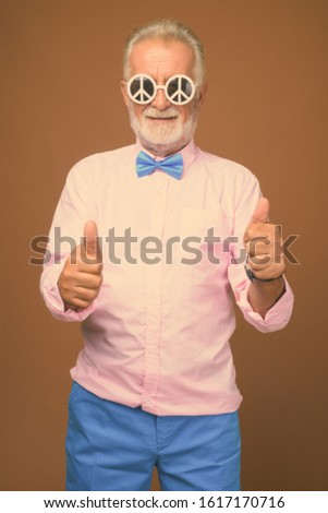 Senior handsome man wearing stylish clothes against brown background