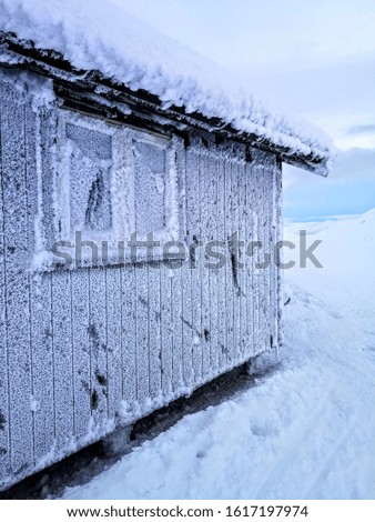 Frosty, cold and old cabin in the mountains. The Windows are frozen and the ice is blokking the view.