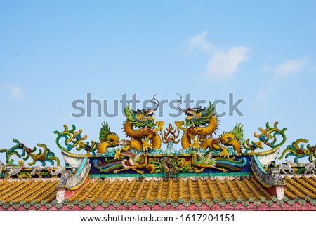Twin dragons statue on the roof of Chinese temple with blue sky in thailand.