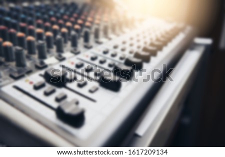 Blurred background of audio equipment, mixers and buttons.