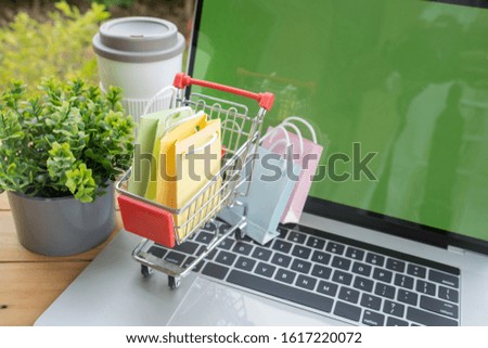 Multi colored tiny paper bag in a tiny trolley, online shopping concept.