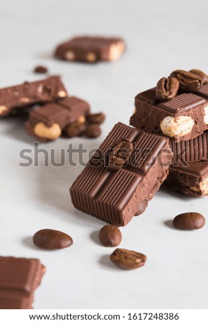 pieces of chocolate with hazelnuts and coffee beans on a marble table