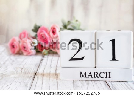 White wood calendar blocks with the date March 22 th for Mother's Day or Mothering Sunday 2020 . Selective focus with pink ranunculus in the background over a wooden table. Royalty-Free Stock Photo #1617252766