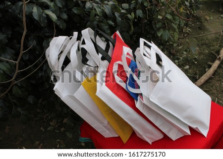 Colored Shopping Bags Isolated on Lush Lava Trends Color Table against natural plant Eco Friendly Background. Non Woven Recyclable Bags. World Environmentally Day Concept. Save earth with ECO.