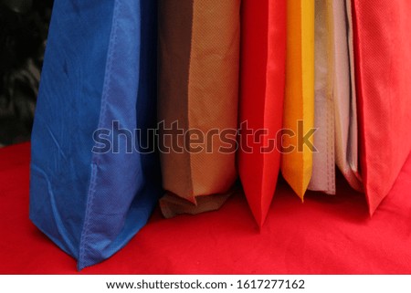 Set of Colorful Shopping Bags Isolated on 2020 Trends Lush Lava Color Table against green plants. Non Woven Gift Bags. Reusable ECO Friendly Bags. World Environmentally Day Concept with Bio Bags